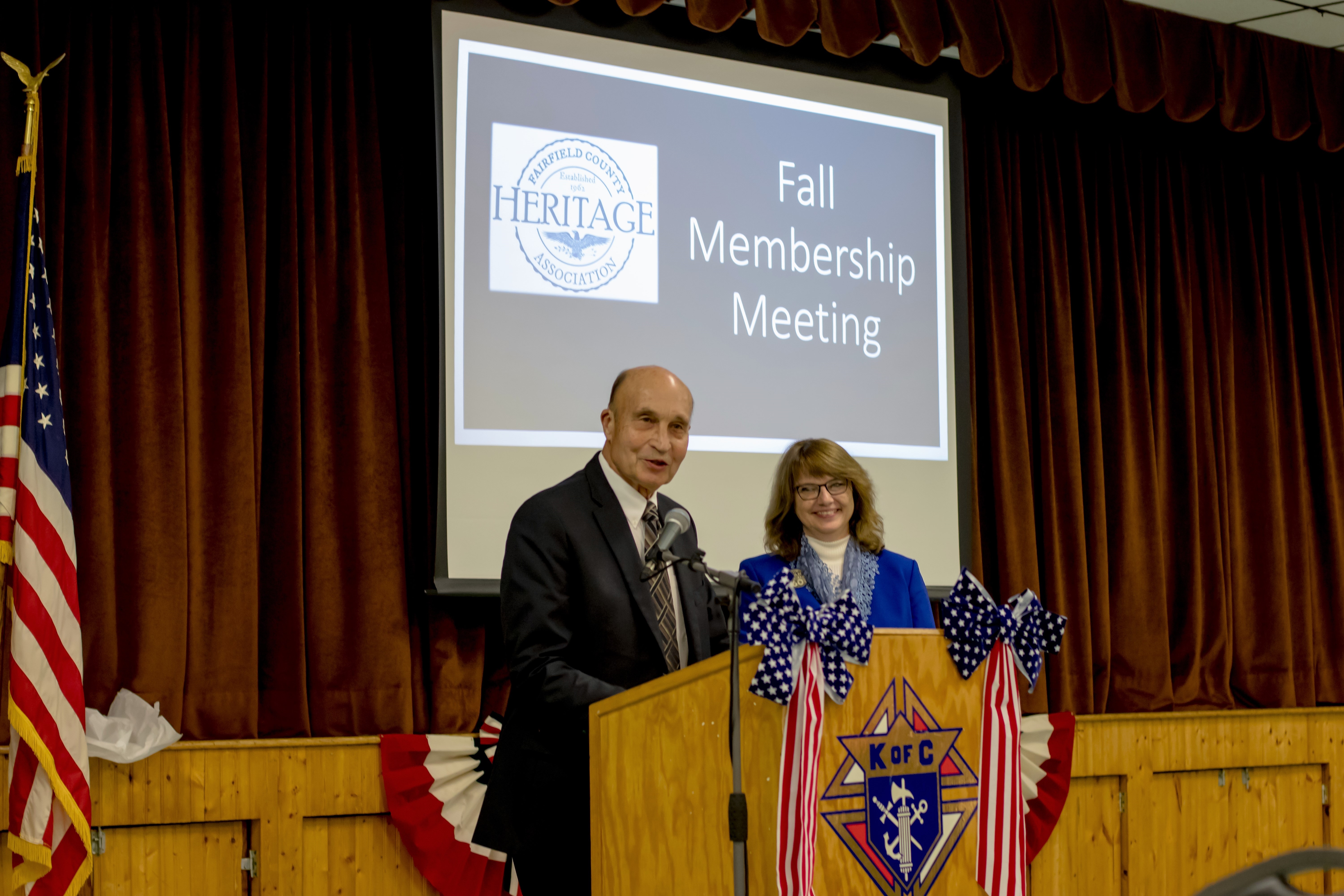 2019 Fall Dinner Membership Meeting - mand and woman speaking at podium
