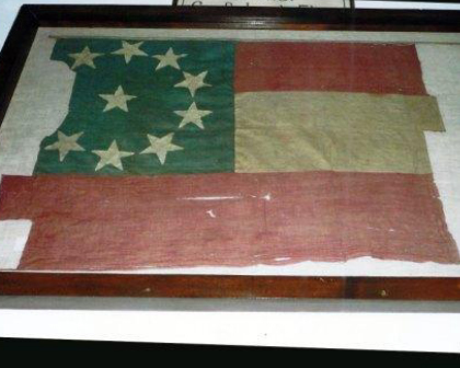 An 11-star handmade silk Confederate national flag, worn and patched, in a wooden display case